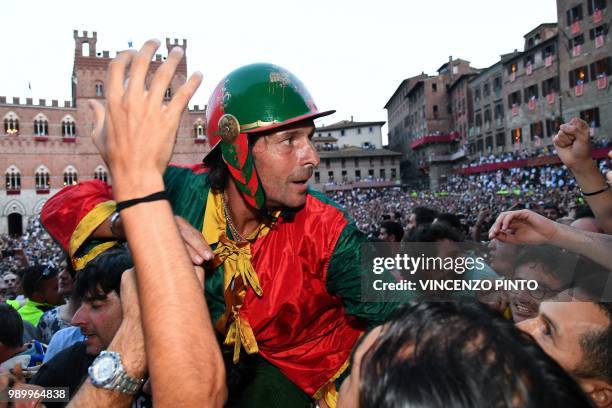 Jockey of the contrada "Drago" Andrea Mari celebrates after winning the historical Italian horse race Palio di Siena on July 2 in Siena.