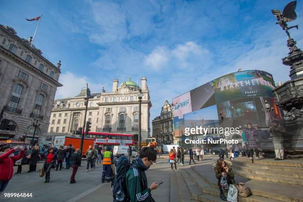 Tourists and locals walking in Piccadilly Circus or sitting on the steps of the Shaftesbury Memorial Fountain in Piccadilly Circus in City of...