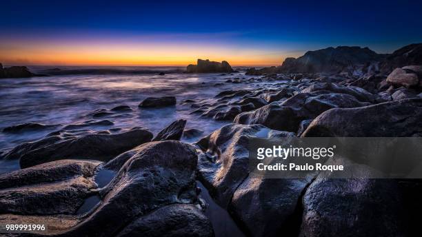rocky coastline and ocean at blue hour, praia norte, portugal - praia do norte stock-fotos und bilder