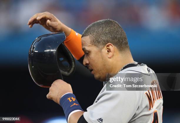 Victor Martinez of the Detroit Tigers puts on his helmet at first base after hitting a single in the seventh inning during MLB game action against...