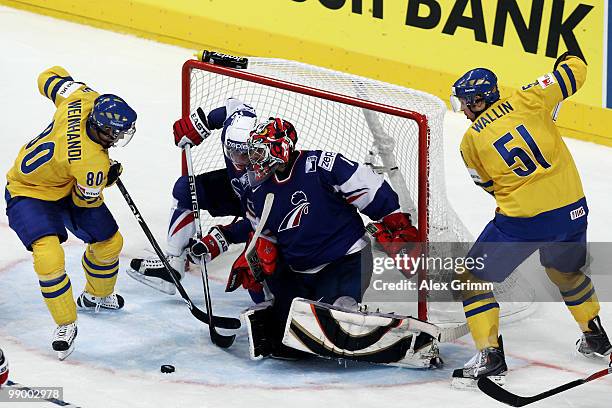 Mattias Weinhandl and Rickard Wallin of Sweden trie to score against Yohann Auvitu and goalkeeper Eddy Ferhi of France during the IIHF World...