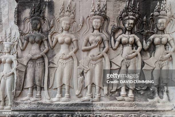 row of carved apsaras, angkor wat, cambodia - apsara stockfoto's en -beelden