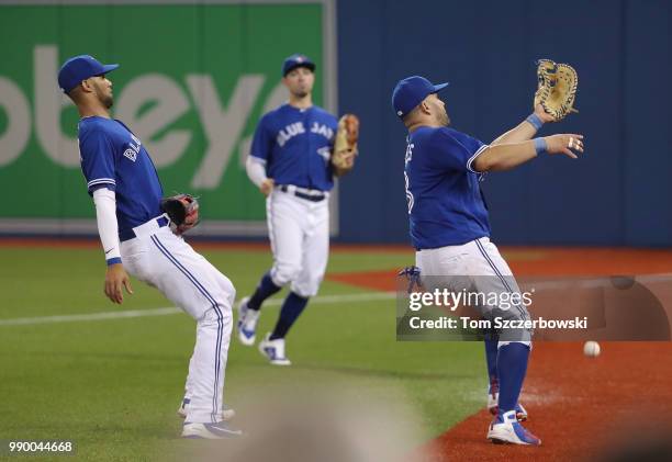 Kendrys Morales of the Toronto Blue Jays cannot catch a foul pop up that drops as Lourdes Gurriel Jr. #13 gets out of his way before they can...