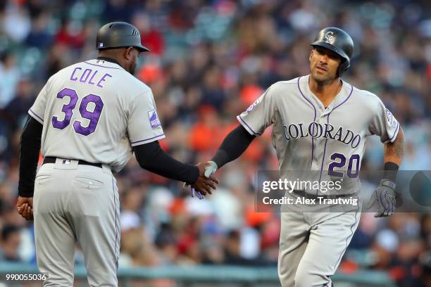 Ian Desmond of the Colorado Rockies celebrates with third base coach Stu Cole after hitting a solo home run in the second inning during a game...