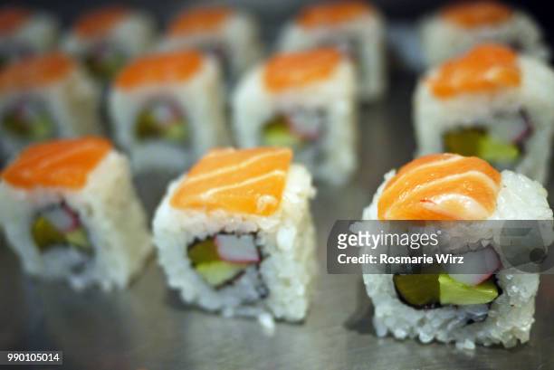 sushi rolls with vegetables and a slice of raw salmon. - rohkosternährung stock-fotos und bilder