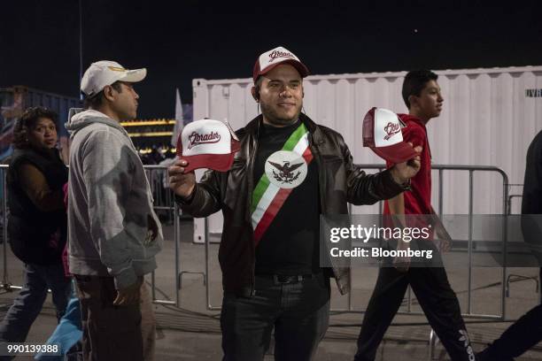 Street vendor holds a campaign hats for sale during an election night rally for Andres Manuel Lopez Obrador, Mexico's president-elect, at Zocalo...
