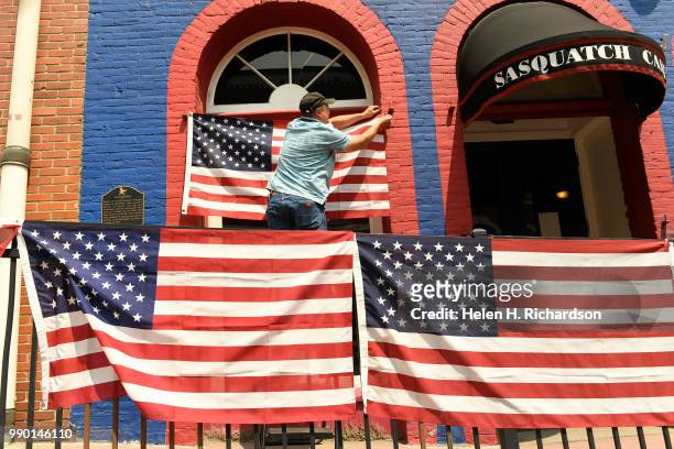 Fred Poston puts up a flag display along Gregory street as he helps prepare the downtown streets for the Fourth of July holiday on July 2, 2018 in...