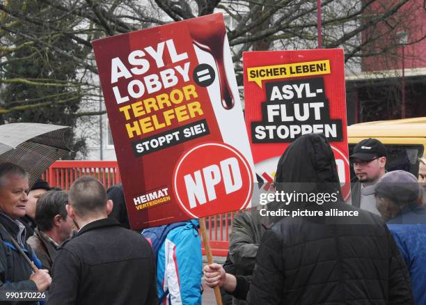 Supporters of the far-right National Democratic Party of Germany hold placards during a protest against receiving asylum seekers in Kandel, Germany,...