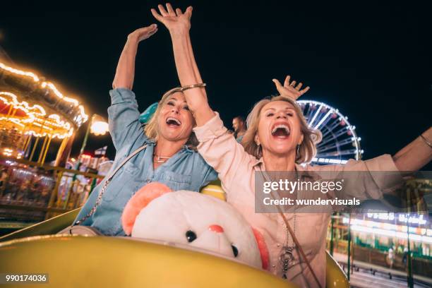 excited senior friends enjoying amusement park roller coaster ride together - old people roller coaster stock pictures, royalty-free photos & images