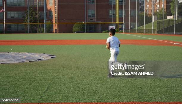Boy runs after a ball during baseball practice at the Nationals Youth Baseball Academy in Washington, DC, on May 7, 2018. - On a searing hot summer's...