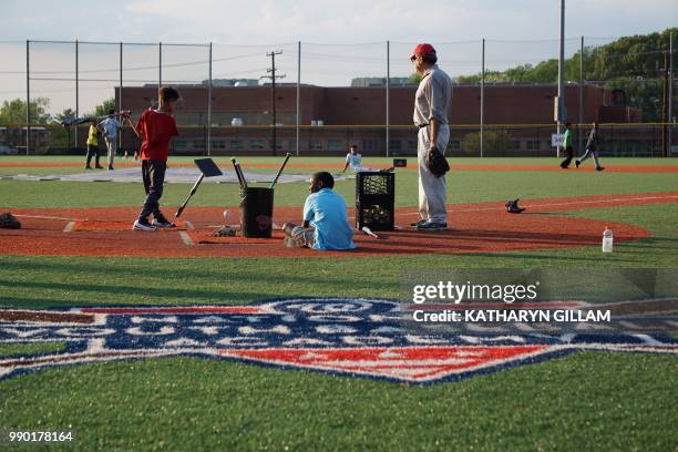 Coach watches children practice their baseball skills at the Nationals Youth Baseball Academy in Washington, DC, on May 7, 2018. - On a searing hot...