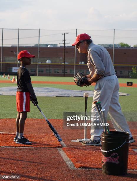 Coach speaks with a boy as he practices baseball skills at the Nationals Youth Baseball Academy in Washington, DC, on May 7, 2018. - On a searing hot...