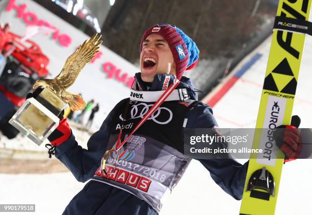 Kamil Stoch of Poland celebrates holding the trophy in his hand after his final jump at the Four Hills Tournament in Bischofshofen, Austria, 6...