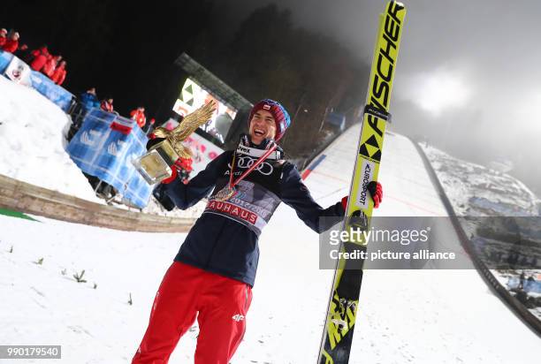 Kamil Stoch of Poland celebrates holding the trophy in his hand after his final jump at the Four Hills Tournament in Bischofshofen, Austria, 6...