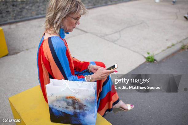 Guest is seen on the street wearing an orange/red/blue/black stripe dress with blue fringe earrings during the Berlin Fashion Week July 2018 on July...