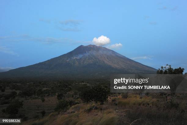 Smoke rises from burning trees on the slopes of Mount Agung volcano after it erupted again, seen from the village of Tulamben in Karangasem Regency...