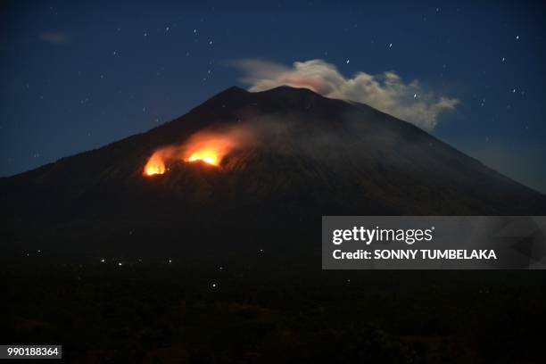 Trees burn on the slopes of Mount Agung volcano after it erupted again, seen in a timed exposure image from the village of Tulamben in Karangasem...