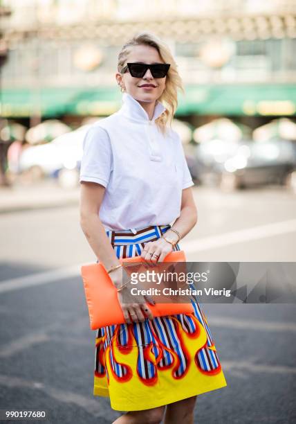 Caroline Daur wearing orange Prada bag, white polo shirt, skirt with fire print, Prada heels is seen outside Schiaparelli on day two during Paris...