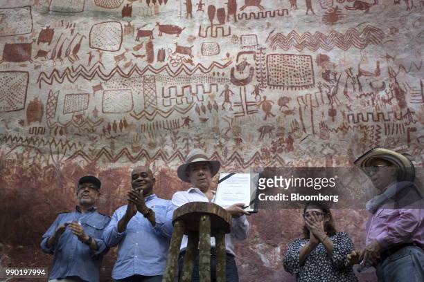 Juan Manuel Santos, Colombia's president, center, displays the document declaring Chiribiquete National Park a world heritage site during a tour of...