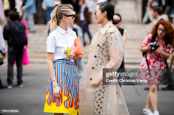 Caroline Daur wearing orange Prada bag, white polo shirt, skirt with fire print, Prada heels and Chriselle Lim wearing trench coat is seen outside...