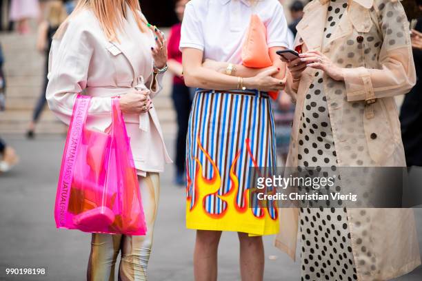 Caroline Daur wearing orange Prada bag, white polo shirt, skirt with fire print, Prada heels and Chriselle Lim wearing trench coat is seen outside...