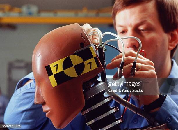 man fixing wiring of crash test dummy - crash test dummies stock pictures, royalty-free photos & images