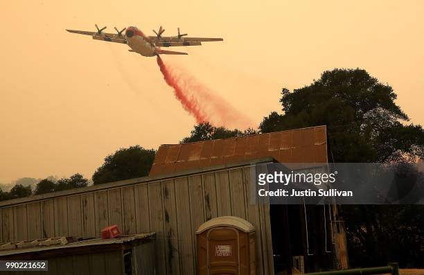 Firefighting air tanker drops Foscheck fire retardant near a structure ahead of the County Fire on July 2, 2018 in Esparto, California. The fast...