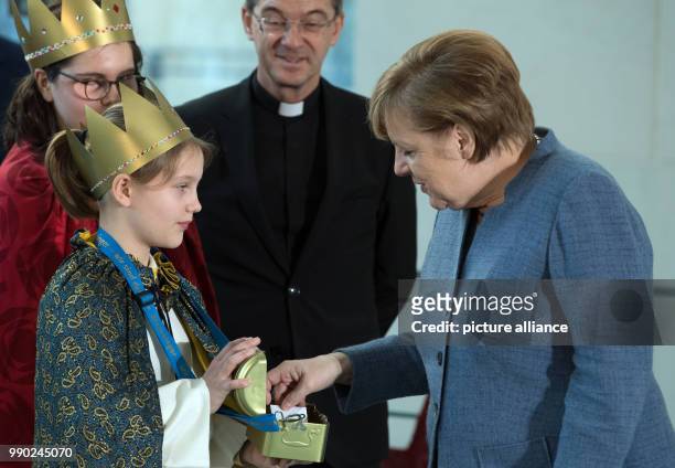 German chancellor Angela Merkel of the Christian Democratic Union gives a donation to the carol singers during the traditional welcoming of the carol...