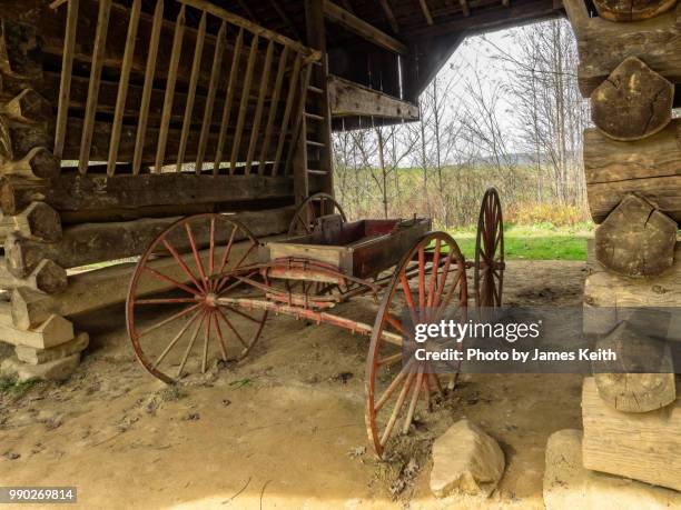 an old wagon slowly disintegrates within the shelter of an aged cantilevered barn in cades cove, great smoky mountains national park. - cades cove foto e immagini stock