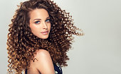 Dense, spring-like,elastic curls in a hairstyle of young, pretty model. Frizzy hair.