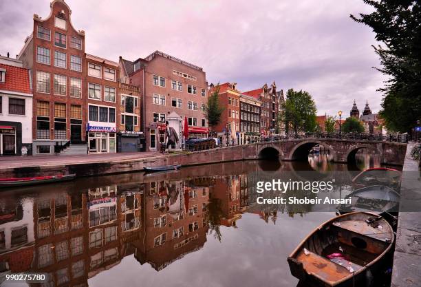 bridge and old building reflected in canal. amsterdam, netherlands - western european culture stock pictures, royalty-free photos & images