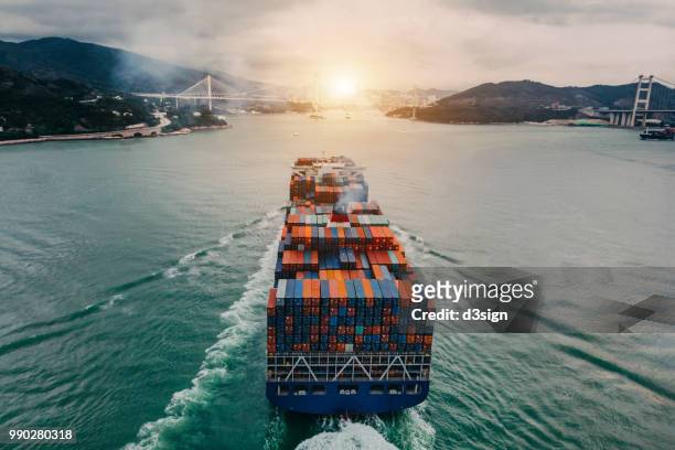 aerial view of container ship transporting goods sailing across ocean entering the port - hong kong transport stock-fotos und bilder