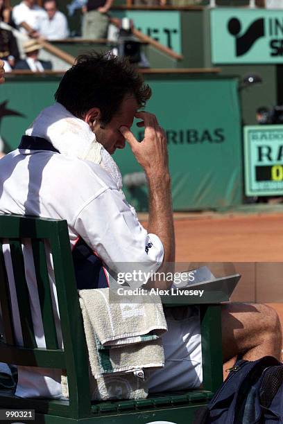 Greg Rusedski of Great Britain gets out his note book at the break after losing the first set in his second round match against Fabrice Santoro of...