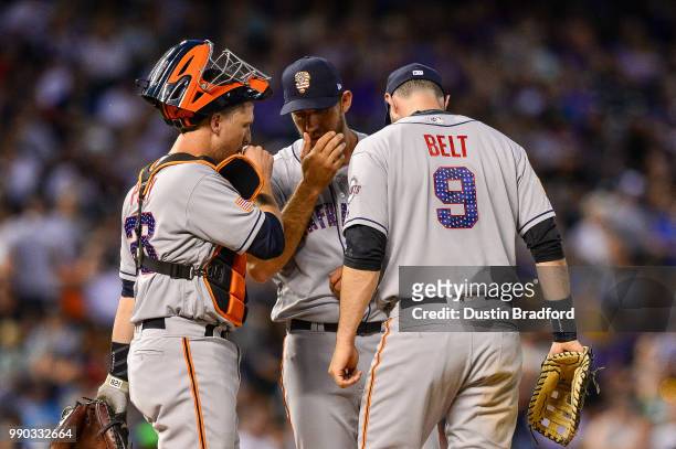 Buster Posey and Brandon Belt of the San Francisco Giants visit Madison Bumgarner on the mound during the seventh inning of a game at Coors Field on...
