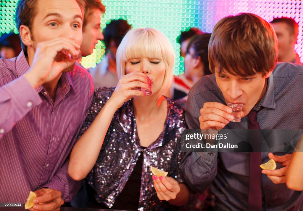 Young people drinking tequila shots in a nightclub