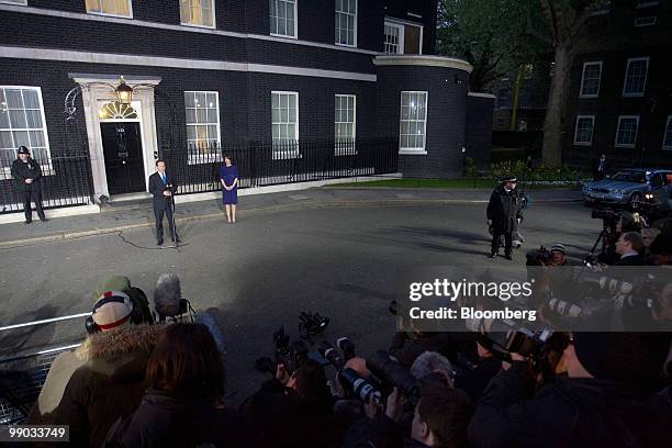 David Cameron, the new U.K. Prime minister, left at microphone, addresses the media as his wife Samantha looks on, right, outside 10 Downing Street...