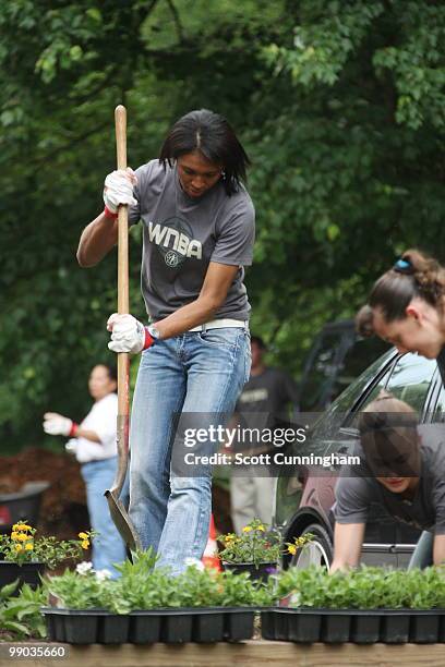 Iziane Castro Marques of the Atlanta Dream helps plant flowers at Collier Heights Park on May 11, 2010 in Atlanta, Georgia. NOTE TO USER: User...