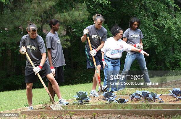 Coco Miller and Kelly Miller of the Atlanta Dream help plant flowers at Collier Heights Park on May 11, 2010 in Atlanta, Georgia. NOTE TO USER: User...