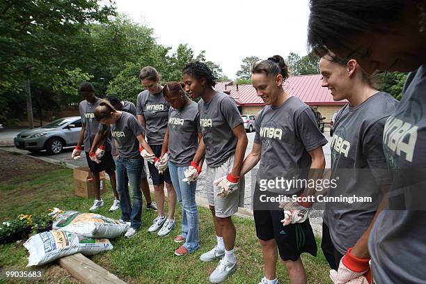 Members of the Atlanta Dream pray before planting flowers at Collier Heights Park on May 11, 2010 in Atlanta, Georgia. NOTE TO USER: User expressly...