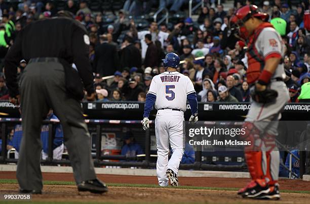 David Wright of the New York Mets walks back to the dugout after striking out with the bases loaded in the first inning as Ivan Rodriguez of the...