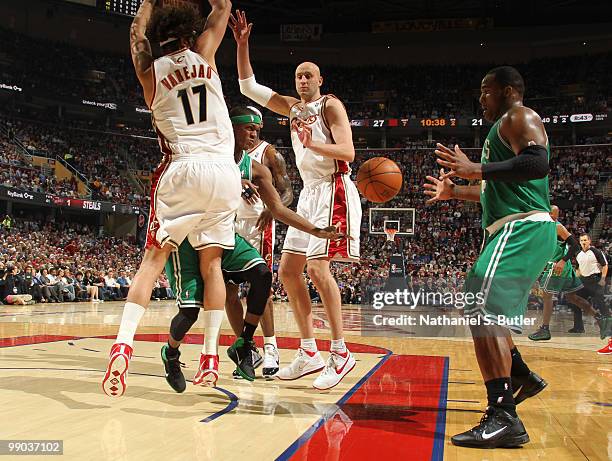 Rajon Rondo of the Boston Celtics passes to teammate Glen Davis while being defended by Zydrunas Ilgauskas and Anderson Varejao of the Cleveland...