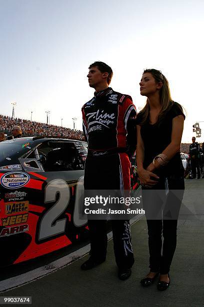 Denny Hamlin, driver of the Z-Line Designs / Operations Helmet Toyota, looks on from the grid with girlfriend Jordan Fish during the performance of...