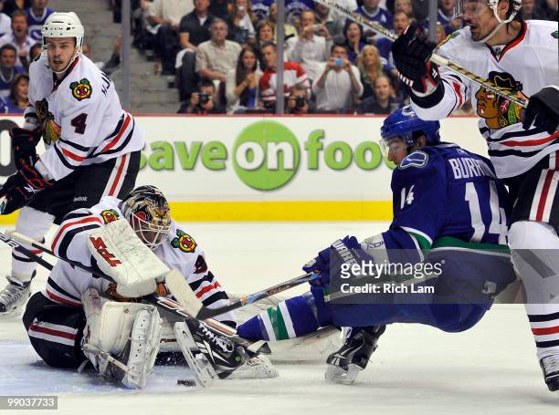 Goalie Antti Niemi of the Chicago Blackhawks scrambles to cover up the puck while Alex Burrows of the Vancouver Canucks tries to get his stick on it...