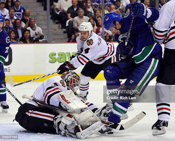 Alex Burrows of the Vancouver Canucks tries to get his stick to the loose puck while goalie Antti Niemi of the Chicago Blackhawks scrambles to cover...