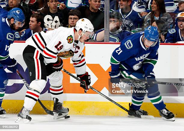 Jonathan Toews of the Chicago Blackhawks and Ryan Kesler and Mason Raymond of the Vancouver Canucks search for the loose puck in Game 6 of the...
