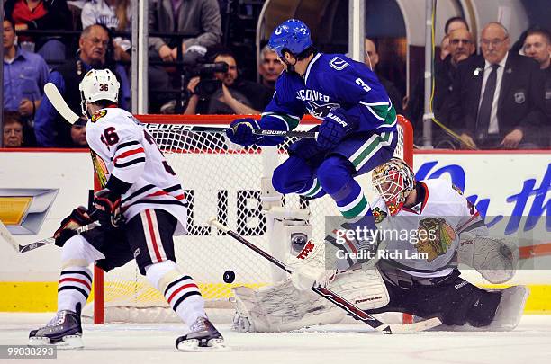 Kevin Bieksa of the Vancouver Canucks jumps out of shot while goalie Antti Niemi of the Chicago Blackhawks makes a save as Dave Bolland of the...