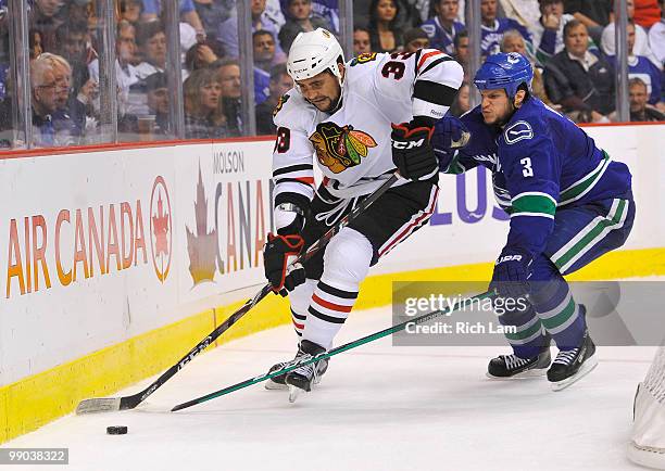 Kevin Bieksa of the Vancouver Canucks tries to check Dustin Byfuglien of the Chicago Blackhawks during the second period in Game Six of the Western...