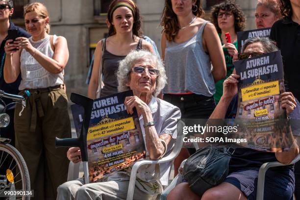 Two women seen showing the poster of the convocation on July 5. The Generalitat of Catalonia intends to auction this week 47 properties from...