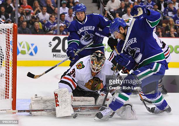 Steve Bernier of the Vancouver Canucks is stopped by goalie Antti Niemi of the Chicago Blackhawks in close while teammate Kyle Wellwood of the...