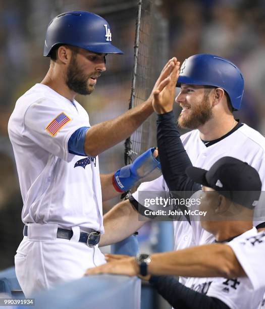 Chris Taylor of the Los Angeles Dodgers is welcomed into the dugout while Max Muncy smiles and Dave Roberts gives a high five after Taylor scored on...